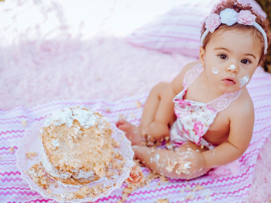 A baby enjoying a first birthday smash cake