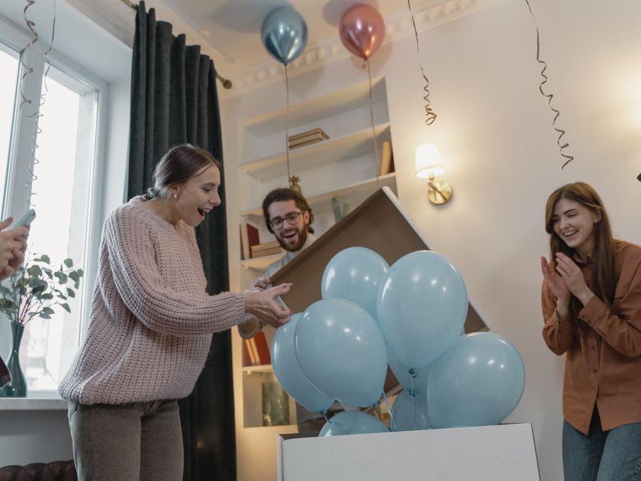 A couple at their gender reveal with blue balloons