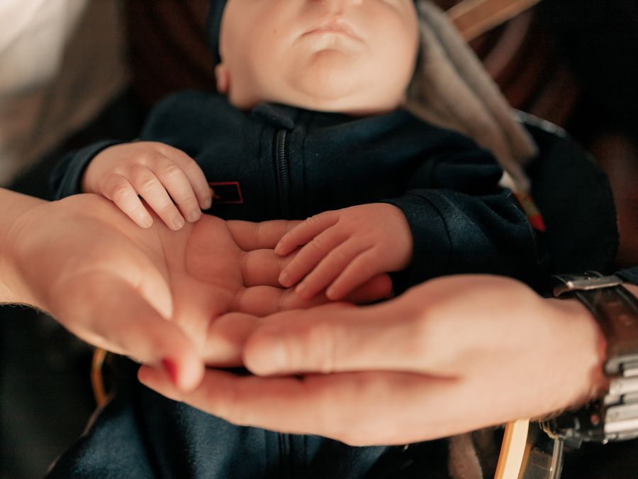 Family hands gently held around a newborn